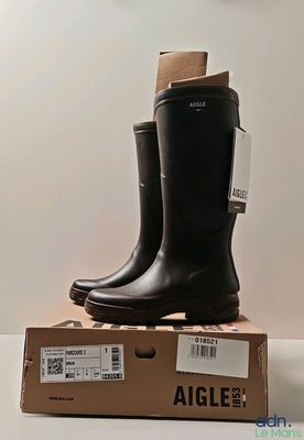 pair of black rain boots sitting on top of a cardboard box