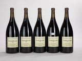 quatre bouteilles de vin sont alignées sur une surface blanche