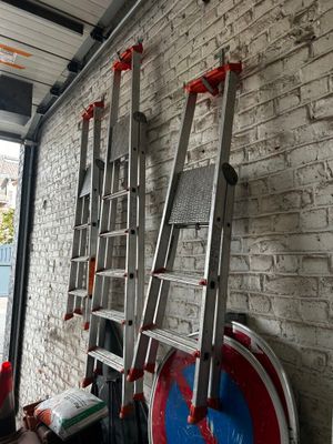 une échelle appuyée contre un mur de briques, à côté d'une borne d'incendie
