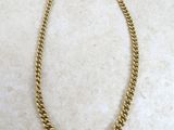 un collier à chaîne en or posé sur une surface en marbre
