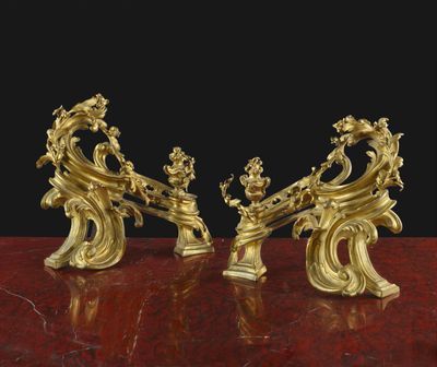 une paire de figurines anciennes en laiton posées sur une table en marbre rouge