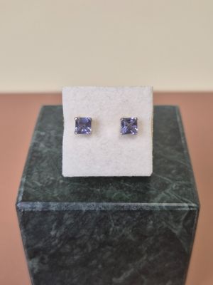 a pair of tanzanite earrings sitting on top of a marble block