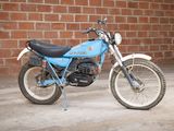 a small blue motorcycle parked in front of a brick wall