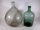 deux bouteilles en verre posées l'une à côté de l'autre sur une surface blanche