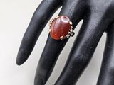 an image of a woman ' s hand wearing a ring with a red stone