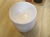 a white cup sitting on a wooden table next to a box of food