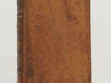 an old book sitting on top of a table next to a white wall