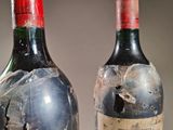 two bottles of wine are sitting on a table covered in plastic