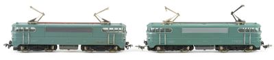 two green trains sitting side by side on a white surface