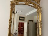a gold mirror hanging on the wall above a red curtain