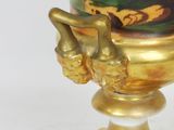 a gold vase with a painting on it sitting on a stand