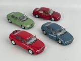 four toy cars sitting in a row on a white surface