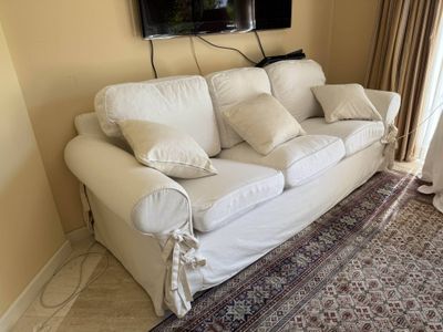 a picture of a living room with a white couch and a flat screen tv