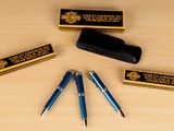 three pens and a pen case sitting on a table