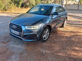 une Audi QX grise garée sur un chemin de terre devant une clôture