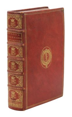 un vieux livre avec une couverture rouge et des bordures dorées sur fond blanc
