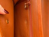 a woman holding a brown purse with a red handle