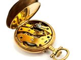 a gold pocket watch that is open on a white surface