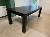 une table noire dans une pièce où se trouve un radiateur dans un coin