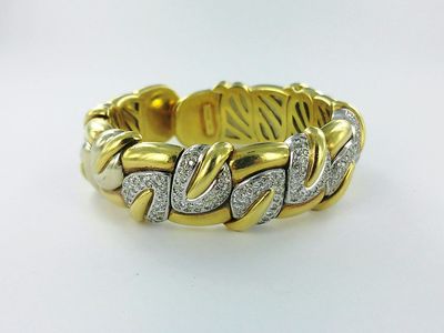 gros plan d'un bracelet en or et en argent sur une surface blanche