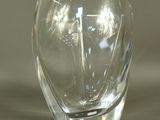 un vase en verre transparent posé sur une table, sur fond blanc