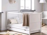 a white crib in the corner of a white room