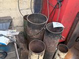 a pile of old metal buckets next to a red door