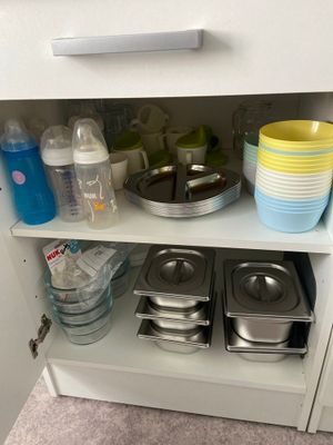 un placard blanc sur lequel sont posés de la vaisselle et des casseroles