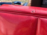 a red piece of luggage sitting on the back of a truck