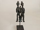 a bronze statue of three people sitting on a wooden base