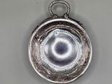 an old silver plate with a circular design hanging from it ' s side