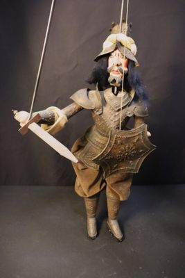 a puppet of a man holding a knife and a sword