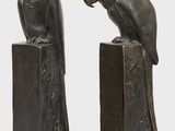 pair of bronze sculptures of parrots sitting on a tree stump