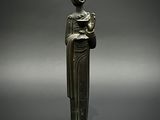 une ancienne statue en bronze représentant une femme tenant un livre