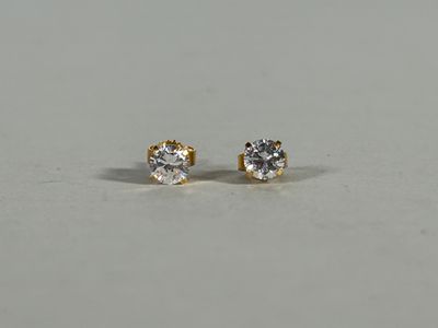 a pair of diamond stud earrings on a white surface