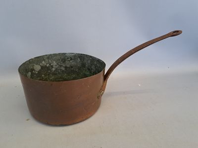 un pot marron muni d'une poignée en bois, posé sur une table