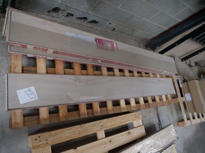 plusieurs pièces de bois sont empilées sur des palettes dans un entrepôt