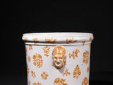 a white and gold vase with a lion head on it