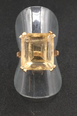 an image of a ring with a yellow topazr on a black surface