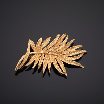 un gros plan d'une broche en feuille d'or posée sur une surface noire