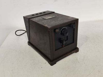 une image représentant un vieil appareil photo posé sur une surface blanche