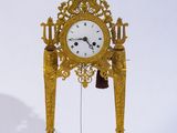une horloge en or posée sur un socle et munie d'une cloche