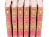 six old books lined up in a row on a white surface