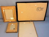 two framed pictures and a picture frame are sitting on a table
