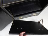 a hand that is holding a black box with gold handles