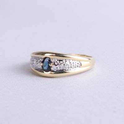 Gros plan sur une bague en or ornée d'un saphir bleu et de diamants