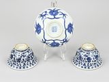 two blue and white vases and a bowl on a stand