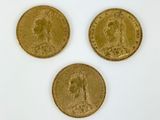 Trois pièces d'or sont représentées sur une surface blanche