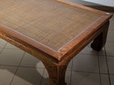a coffee table with a woven top on a tiled floor