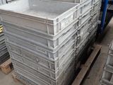 une grande pile de récipients en plastique posée sur des palettes dans un entrepôt